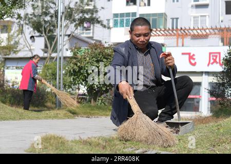 201115 -- YUPING, Nov. 15, 2020 -- Yao Maozhong R, a relocated villager, cleans up fallen leaves at the relocation community where some of the relocated villagers from Tiejiaxi Village live in Yuping Dong Autonomous County, southwest China s Guizhou Province, Nov. 14, 2020. Tiejiaxi Village used to be one of the 14 villages plagued by poverty in the county. Since 2014, the local government has made great effort to help villagers shake off poverty. On the one hand, the local government improved the innfrastructure and tried to lead villagers to engage in eco-agricultural industry, and on the ot Stock Photo