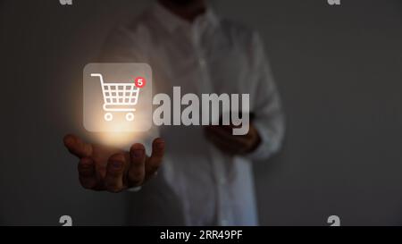 Red shopping baskets and parcel box with cart image on box float in the air above a smartphone for online shopping concept design. Stock Photo