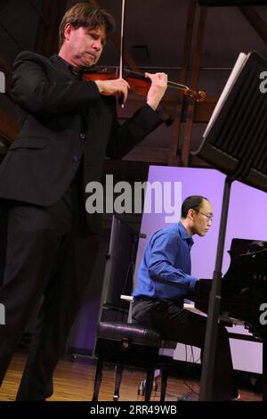 201126 -- WELLINGTON, Nov. 26, 2020 -- Pianist Liu Jian back and violinist Martin Riseley perform during China Crossing IV, a concert featuring a mixture of Chinese and Western music in Wellington, New Zealand, Nov. 26, 2020. New Zealand School of Music and the Confucius Institute of Victoria University of Wellington co-hosted a concert featuring a mixture of Chinese and Western music here on Thursday. Photo by /Xinhua NEW ZEALAND-WELLINGTON-CHINA CROSSING-CONCERT MengxTao PUBLICATIONxNOTxINxCHN Stock Photo