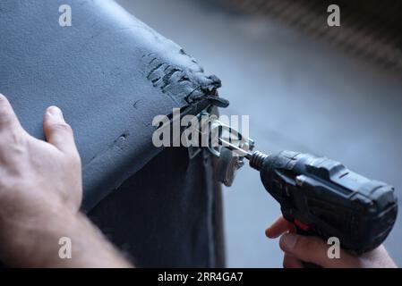 cordless screwdriver that wraps a screw into a hole in a sofa close up Stock Photo