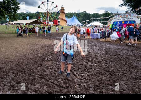 A young boy gets stuck in the mud in rainy weather near the food stalls at Green Man Festival, Brecon, Wales, UK, 2023. Photo: Rob  Watkins Stock Photo