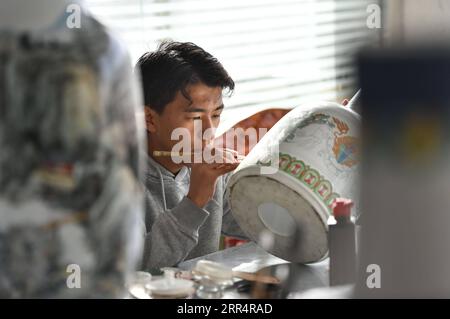 201212 -- LHASA, Dec. 12, 2020 -- A student majored in thangka painting in the Tibet Vocational Technical College works on a ceramic vase at a cultural development company in Lhasa, capital of southwest China s Tibet Autonomous Region, Dec. 3, 2020.  Xinhua Headlines: Vocational training cultivates dreams, fortunes for Tibetans JigmexDorje PUBLICATIONxNOTxINxCHN Stock Photo