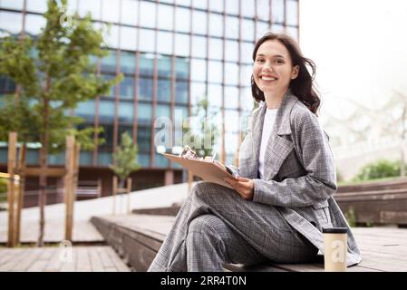 Business Lady Working With Papers Sitting In Urban Area Outdoors Stock Photo