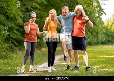 Senior man having leg injury during group training with friends outdoors Stock Photo