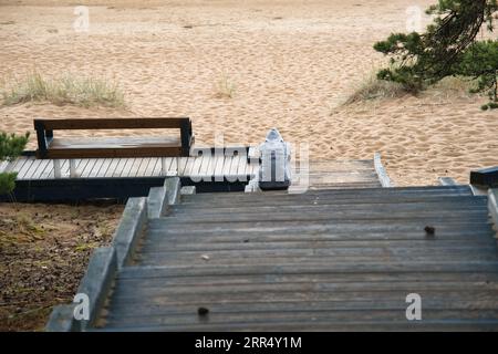 A sad young man sits on the shore of Lake Peipus. Sitting on steps on a sandy beach Stock Photo