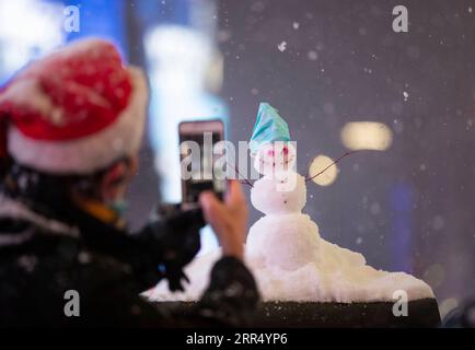 201217 -- NEW YORK, Dec. 17, 2020 -- A man takes photos of a snowman on Times Square in New York, the United States, Dec. 16, 2020. A snow storm hit New York on Wednesday.  U.S.-NEW YORK-SNOW WangxYing PUBLICATIONxNOTxINxCHN Stock Photo