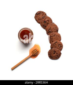Conceptual composition honey in a bowl, dipper, homemade chocolate cookies with chocolate pieces on a white background flat lay top view. Stock Photo
