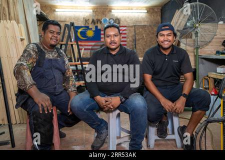 201221 -- KUALA LUMPUR, Dec. 21, 2020 -- From L to R Noor Adzrene Mohd Noor, Mohamad Hafiz Johari, and Abdul Razak Abdul Latif pose for photos at Kawood workshop on the suburbs of Kuala Lumpur, Malaysia, Dec. 18, 2020. Mohamad Hafiz Johari, together with two other former photographers Abdul Razak Abdul Latif and Noor Adzrene Mohd Noor, came together to set up Kawood, a combination of the Malay word kawan friend and wood, with all three having lost their source of income due to disruptions caused by the COVID-19 pandemic. Undeterred, they brainstormed some means of making a living, ultimately d Stock Photo