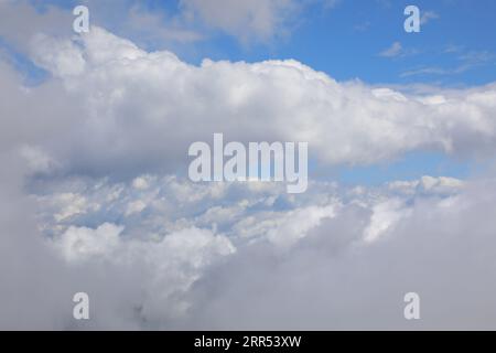 view of the white clouds and blue sky from the window of an aircraft during the intercontinental journey Stock Photo