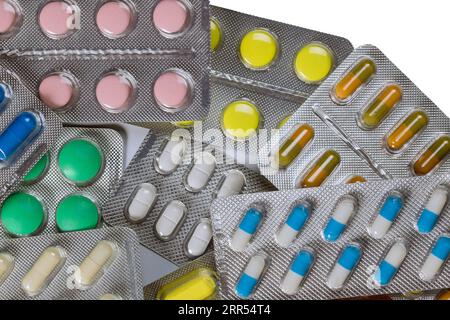 Colorful pills, tablets, capsules are arranged in various pharmaceutical medicine blisters, which are set against an isolated white background. Stock Photo