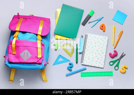 Composition with stylish school backpack and different stationery on grey background Stock Photo