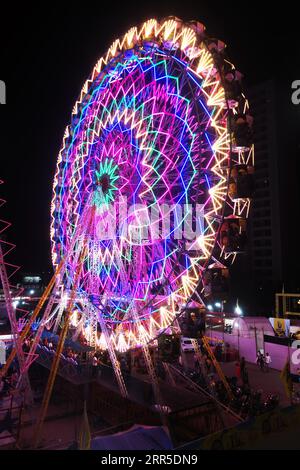 Rajkot, India. 6th September, 2023. Portrait view of a giant Ferris wheel with heavy neon lights shimmering near big bazaar 150 feet Ring Road in Rajkot. Credit: Nasirkhan Davi/Alamy Live News Stock Photo