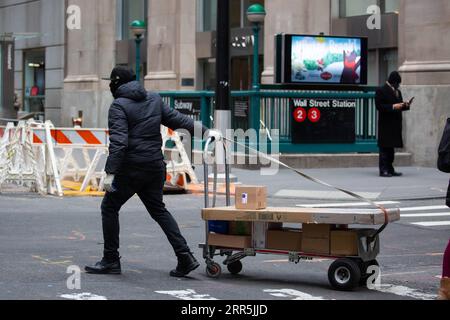210109 -- NEW YORK, Jan. 9, 2021 -- A delivery worker rolls packages across Wall Street in New York, United States, Jan. 8, 2021. U.S. employers slashed 140,000 jobs in December, the first monthly decline since April 2020, as the recent COVID-19 spikes disrupted labor market recovery, the Labor Department reported Friday. The unemployment rate, which has been trending down over the past seven months, remained unchanged at 6.7 percent, according to the monthly employment report. Photo by /Xinhua U.S.-NEW YORK CITY-COVID-19-UNEMPLOYMENT RATE MichaelxNagle PUBLICATIONxNOTxINxCHN Stock Photo