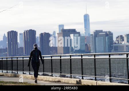 210109 -- NEW YORK, Jan. 9, 2021 -- A woman walks along the East River at a park in New York, the United States, on Jan. 9, 2021. The total number of COVID-19 cases in the United States topped 22 million on Saturday, according to the Center for Systems Science and Engineering CSSE at Johns Hopkins University.  U.S.-NEW YORK-COVID-19-CASES-22 MILLION WangxYing PUBLICATIONxNOTxINxCHN Stock Photo
