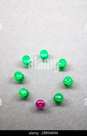 Group of thumbtacks formed in circle where one is differentiated by color Stock Photo