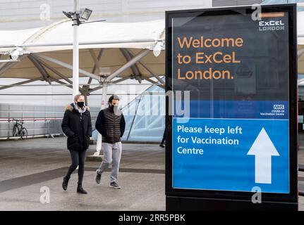 210113 -- LONDON, Jan. 13, 2021 -- People wearing face masks walk past the Vaccination Centre at ExCel exhibition centre in London, Britain, Jan. 12, 2021. British Prime Minister Boris Johnson on Monday warned against false complacency as the country is seeking to speed up the coronavirus vaccine rollout. According to the prime minister, 2.4 million coronavirus jabs have been administered across Britain. Seven new mass vaccination sites in England opened Monday, as the country races against time to bring the pandemic under control.  BRITAIN-LONDON-COVID-19-VACCINE ROLLOUT HanxYan PUBLICATIONxN Stock Photo