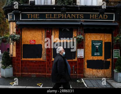 210120 -- LONDON, Jan. 20, 2021 -- A man wearing a face mask walks past a closed pub in London, Britain, on Jan. 19, 2021. The number of people who have died within 28 days of a positive coronavirus test has surpassed the grim milestone of 90,000 in Britain after another 1,610 were confirmed, according to official figures released Tuesday. The latest daily death toll, the highest since the pandemic began in the country, brought the total number of coronavirus-related deaths in Britain to 91,470, the data showed.  BRITAIN-LONDON-COVID-19-DEATH TOLL HanxYan PUBLICATIONxNOTxINxCHN Stock Photo