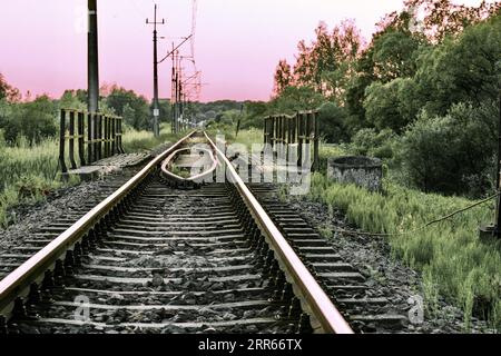 Railway tracks and rails in the countryside against the backdrop of a beautiful sunset. Stock Photo