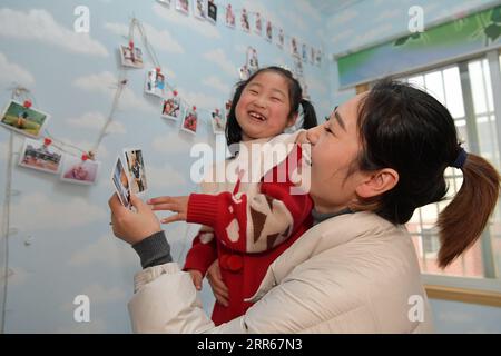 210130 -- NANCHANG, Jan. 30, 2021 -- Wang Ajing, an attendant of the China Railway Nanchang Bureau Group Co., Ltd., together with her daughter, look at photos of their family members at her home in Jiujiang City of east China s Jiangxi Province, Jan. 25, 2021. 30-year-old Wang Ajing, who is from Xianyang City of northwest China s Shaanxi Province, is now serving as an attendant of the China Railway Nanchang Bureau Group Co., Ltd. Before she left her hometown in 2008, Wang s parents gave her a family photo, which she carried with her ever since then. Wang s mother, for some reason, was not able Stock Photo