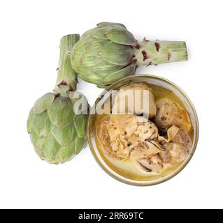 Bowl with delicious artichokes pickled in olive oil and fresh vegetables on white background, top view Stock Photo