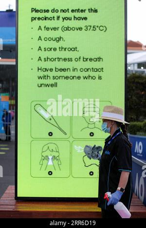 210207 -- BEIJING, Feb. 7, 2021 -- A woman walks past a screen displaying COVID-19 precaution measures at Melbourne Park, in Melbourne, Australia, on Feb. 6, 2021. The Australian Open tennis tournament is scheduled to start on Feb. 8.  XINHUA PHOTOS OF THE DAY BaixXuefei PUBLICATIONxNOTxINxCHN Stock Photo