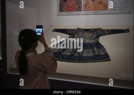210210 -- BEIJING, Feb. 10, 2021 -- A visitor takes photos during an exhibition featuring ancient Chinese costumes at the National Museum of China, Beijing, capital of China, Feb. 10, 2021. The National Museum of China has opened its first exhibition on the general history of Chinese costume, taking visitors on a journey through the evolution of ancient Chinese costume over thousands of years. On display are about 130 pieces or sets of cultural relics, including jade, stone and bone artifacts, figurines, clothing, gold and silver accessories, painting and calligraphy works. The items provide a Stock Photo