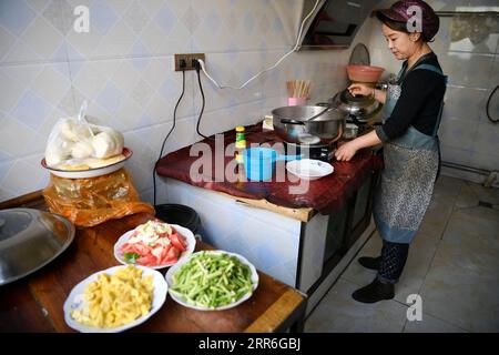 210214 -- YINCHUAN, Feb. 14, 2021 -- Zhang Junming s daughter-in-law prepares lunch one day before the Chinese Lunar New Year at the new residence at the Binhe Jiayuan relocation site in Yinchuan, northwest China s Ningxia Hui Autonomous Region, Feb. 11, 2021. Zhang Junming, 55, once lived in Hongbaiyang Township, an economic backwater in southern Ningxia. When he was young, Zhang had been severely injured in an accident, and hence suffered from leg disabilities that prevented him from seeking job opportunities in the big cities. So he and his family had to scrape a living out of poor yields o Stock Photo