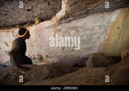 210223 -- SYDNEY, Feb. 23, 2021 -- File photo taken on July 15, 2016 shows an aborigine looking at a rock painting of kangaroo in Kimberley region, Australia. A two-meter-long painting of a kangaroo in Western Australia s Kimberley region has been recognized as Australia s oldest intact rock painting, dating back 17,300 years. Naturalistic depictions of animals are a common subject for the world s oldest dated rock art. In a paper published in Nature Human Behavior on Tuesday, a research team led by the University of Melbourne used the radiocarbon dating of 27 mud wasp nests from 16 similar pa Stock Photo