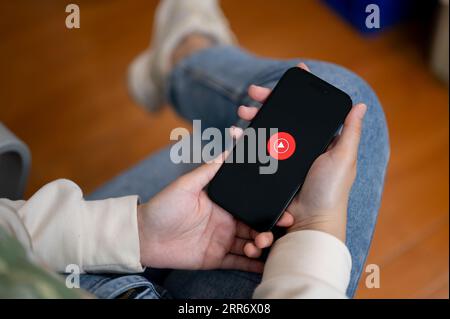 Chiang mai, Thailand - Sep 06 2023: Close-up image of a female holding an iPhone14 with a Youtube music logo on screen. Youtube music logo. A woman us Stock Photo