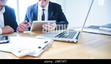 Two businessman using digital tablet and laptop discussing ideal at meeting . Stock Photo