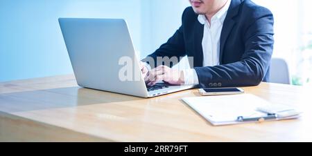 Close up view of businessman using laptop on wooden table. Stock Photo