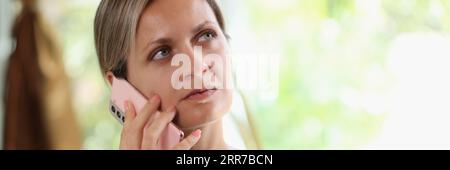 Thoughtful female speaking on smartphone at home Stock Photo