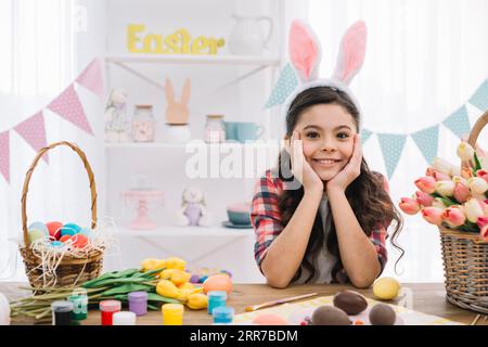 Portrait girl with easter eggs paint tulips flowers table Stock Photo