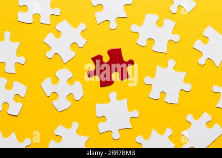 Red bright puzzle among white against yellow backdrop Stock Photo