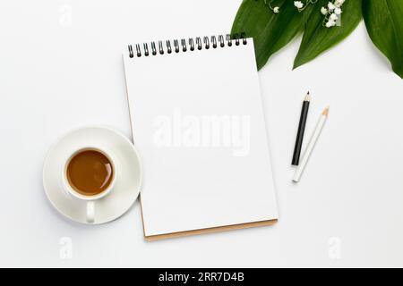 Coffee cup blank spiral notepad colored pencils with leaves flower office desk Stock Photo