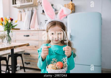 Girl bunny ears holding basket with easter eggs Stock Photo
