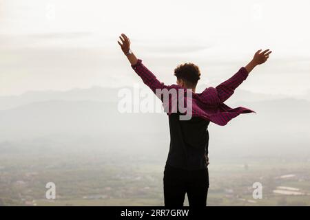 Rear view young man with raised hand Stock Photo