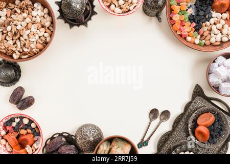 Dried fruits nuts dates lukum baklava metallic bowl white backdrop with space center Stock Photo