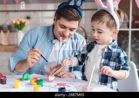 Father son painting eggs easter together Stock Photo