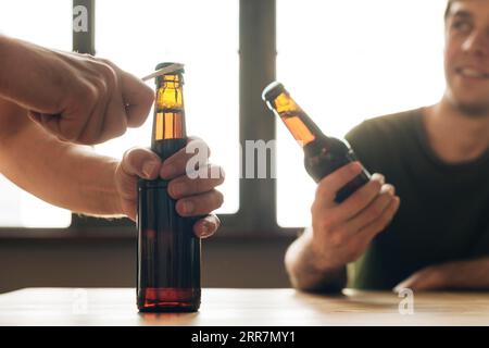 Man looking person opening brown beer bottle restaurant Stock Photo