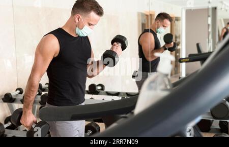 Man working out gym while wearing medical mask Stock Photo