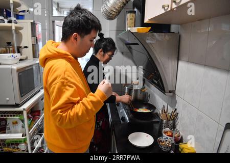 210402 -- TIANJIN, April 2, 2021 -- Wu Guixiang helps her son Zhang Hao, diagnosed with autism, prepare dinner in Hebei District, north China s Tianjin, March 29, 2021. In 1998, Zhang Hao was diagnosed with autism at the age of two. Ever since the diagnosis, Zhang s mother Wu Guixiang has spent all her time looking after her son. In order to help Zhang Hao and eight others with autism improve their social engagement after they had become grown-ups, Wu set up an autism training center in 2016, providing them with courses on life, social and vocational skills. Within five years, Zhang Hao learne Stock Photo