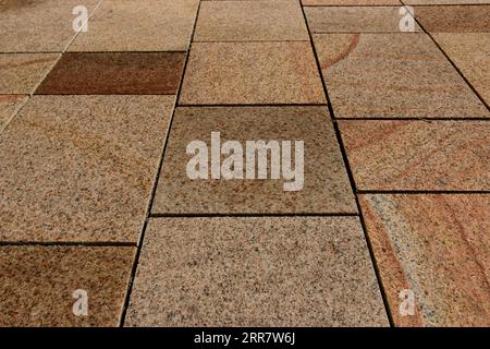 red brown stone paved sidewalk in diminishing perspective view. flat level smooth pavement. open joints. pattern and texture. parks, outdoor. walkway Stock Photo