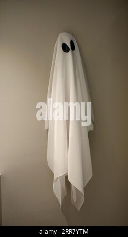 A ghost covered white Halloween dress sheet was hanged on the hook at the wall, breaking time, take a break, funny Halloween concept, party costume, h Stock Photo