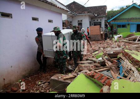 210411 -- EAST JAVA, April 11, 2021 -- People move a freezer near damaged houses after a 6.1 magnitude quake hit Majang Tengah village in Malang, East Java, Indonesia, April 11, 2021. Six people were killed, another one was seriously injured, and scores of buildings were damaged after a 6.1-magnitude quake rocked Indonesia s western province of East Java on Saturday, officials said. The earthquake struck at 2 p.m. Jakarta time 0700 GMT with the epicenter 96 km south of Kepanjen town of Malang district with a depth of 80 km, Andry Sembiring, an official at the Meteorology, Climatology and Geoph Stock Photo