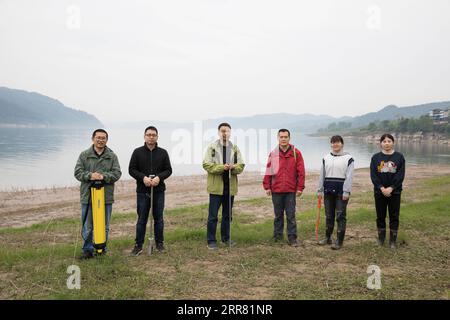 210412 -- ZHONGXIAN, April 12, 2021 -- Researchers pose for a photo at water level fluctuation zone of the Three Gorges Reservoir in Zhongxian County, southwest China s Chongqing, April 10, 2021. The Three Gorges project is a vast multi-functional water-control system on the Yangtze River, China s longest waterway, with a 2,309-meter-long and 185-meter-high dam. The water levels of the reservoir area inevitably fluctuate on an annual discharge-storage cycle between 145m to 175m at the dam. The water level fluctuation zone also encounters some eco-environmental problems, including soil erosion Stock Photo
