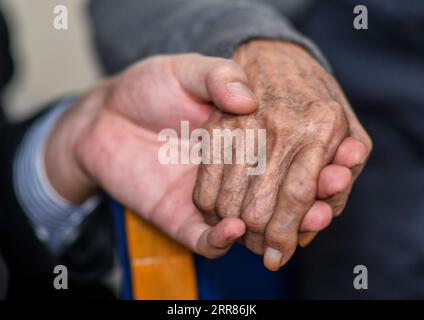 210421 -- URUMQI, April 21, 2021 -- Niu Ruiqing L holds the hand of his grandfather Niu Jiashan R at home in Urumqi, northwest China s Xinjiang Uygur Autonomous Region, on Feb. 24, 2021. A career relay of three generations over 70 years within the same family has witnessed the astonishing development of railway transportation in northwest China s Xinjiang Uygur Autonomous Region. Xinjiang has always been well noted for its harsh geological and climate environment ranging from vast deserts, snow-clad mountains, devastating winds, to salty marshes, all of them natural enemies to railway construc Stock Photo