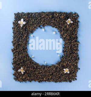 Mockup of dried tea leaves and fresh jasmine flowers shaped in square clock Frame isolated on plain light blue background Stock Photo