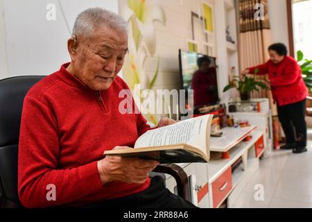 210424 -- TAIYUAN, April 24, 2021 -- Zhang Lianggui reads at his home in north China s Shanxi Province, March 10, 2021. Zhang Lianggui, his son Zhang Hai and grandson Zhang Shiqi had all worked as coal miners. The striving history of this family of coal miners across three generations, epitomizes the rise of China s coal mining industry, from man-driven to technology-driven. Nearly 90 years old, Zhang Lianggui is a retired coal miner. Recruited in 1954, he recalls the harsh working conditions for coal miners back in the day, many of whom had to bend over in narrow, low tunnels. I always felt t Stock Photo