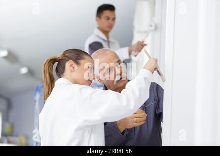 guiding a trainee in painting a corner Stock Photo